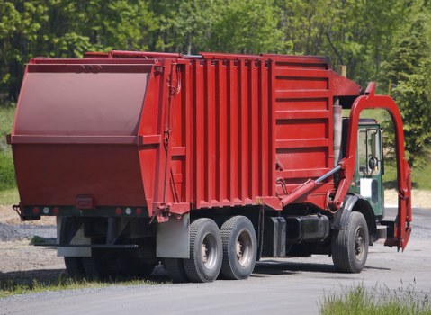Operative wearing PPE loading commercial refuse onto truck